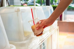 A hand holding a plastic cup with a straw