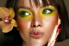 Woman with bright makeup and flower in her hair pulling a playful face