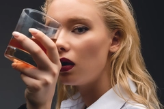 Image Woman holding a glass of whiskey in front of her face